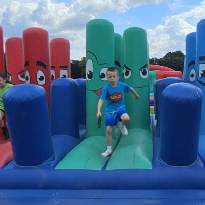 Two kids running accorss an It's A Knockout inflatable obstacle